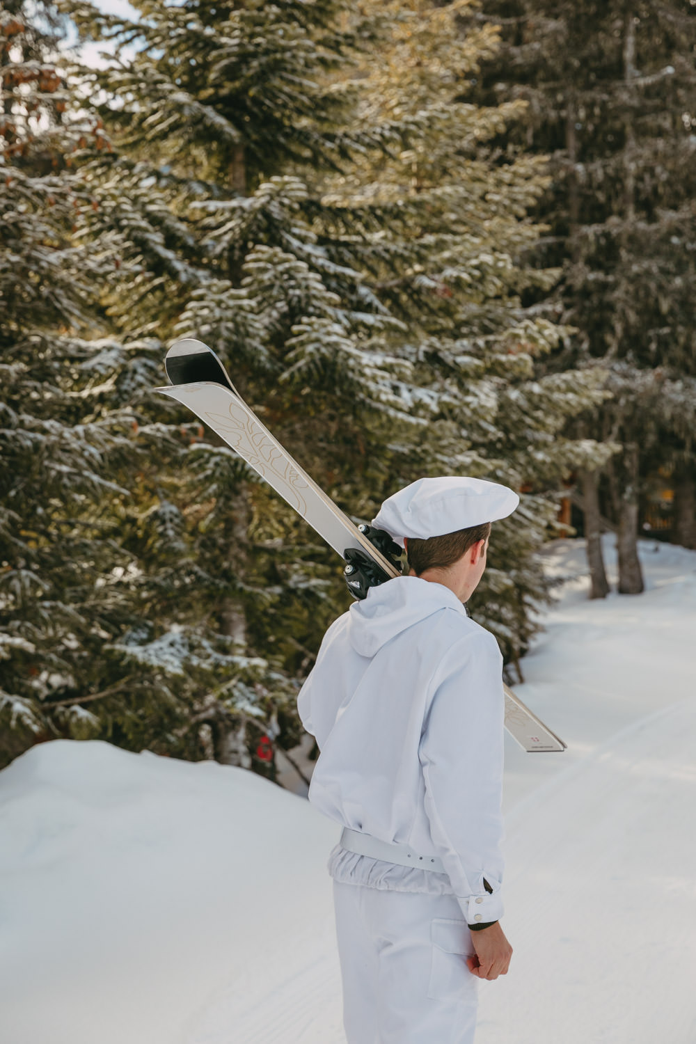 staff in white uniform, holding a pair of skis on the ski slopes at Airelles Courchevel
