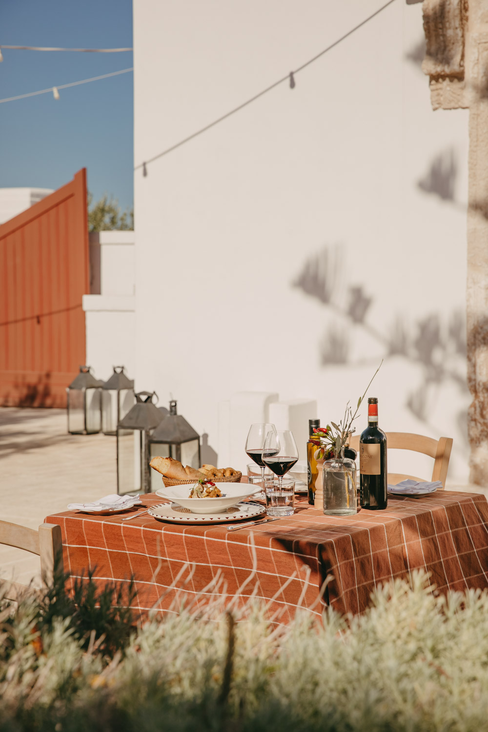 a table with orange checkered cloth, wine and pasta