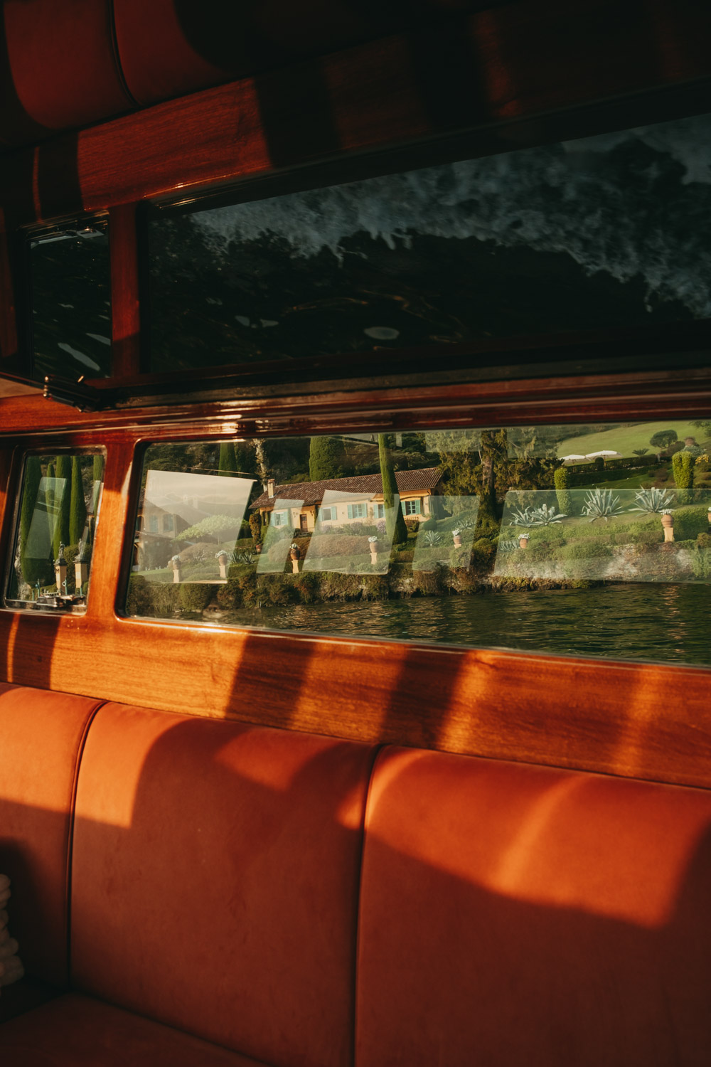 view of a private villa through the window of a boat on lake como