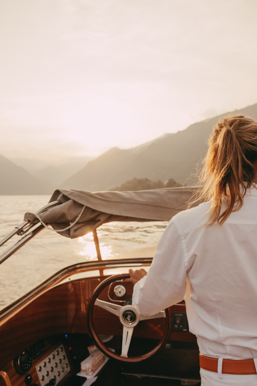 woman sailing a boat on lake como at sunset