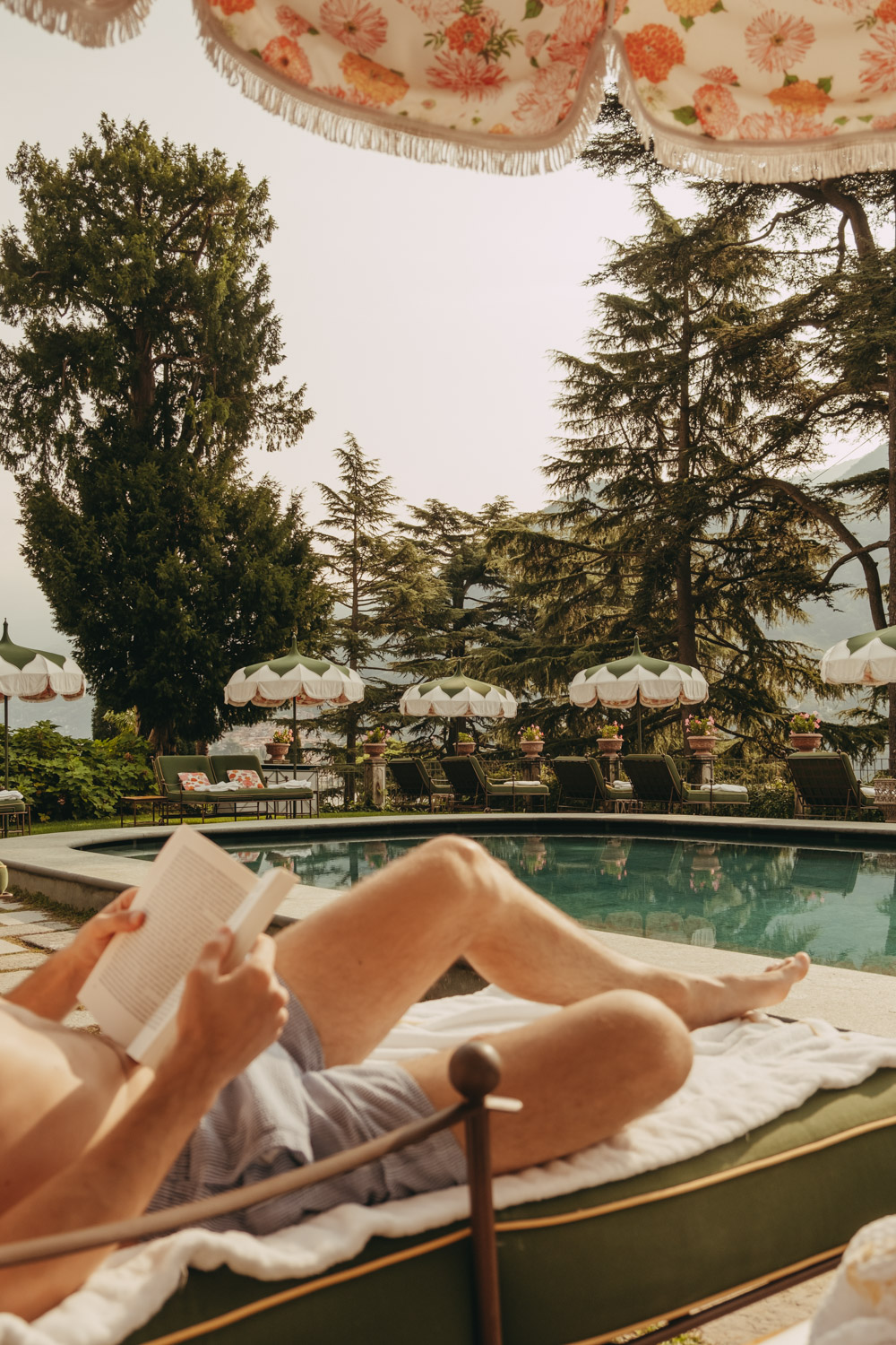 man reading a book by the pool at passalacqua